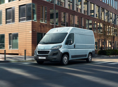 A Peugeot electric school minibus driving along a city road.